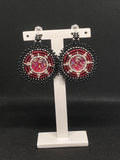 Red and black beaded round drop earrings on a white stand